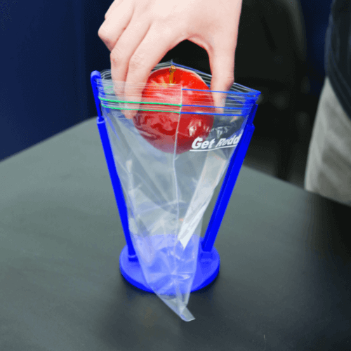 Hand putting apple in transparent storage bag